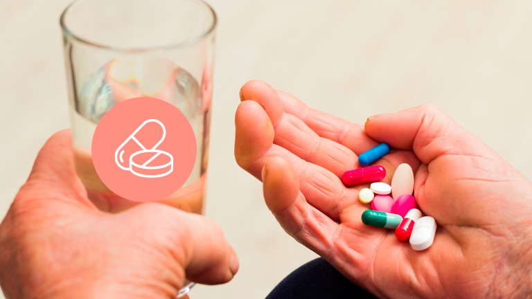 Medicação na mão do utente e um copo com água